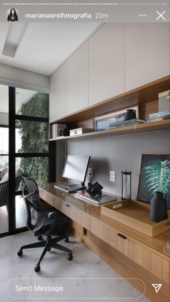 an office with a desk, computer monitor and chair in front of a large window