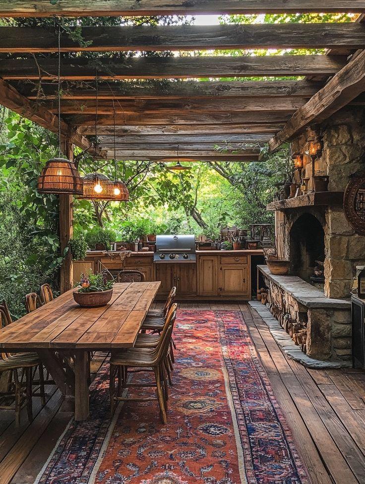 an outdoor kitchen and dining area with wood flooring, stone fireplace, and wooden table